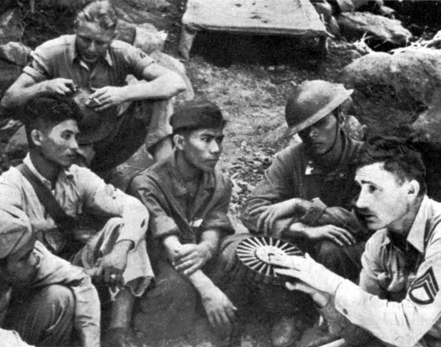 Photo of Filipino soldiers gathered around an American officer holding a drum magazine