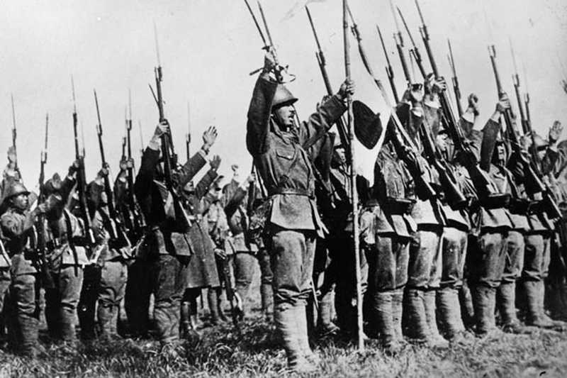 Black and white photo of Japanese soldiers raising their rifles into the air, celebrating