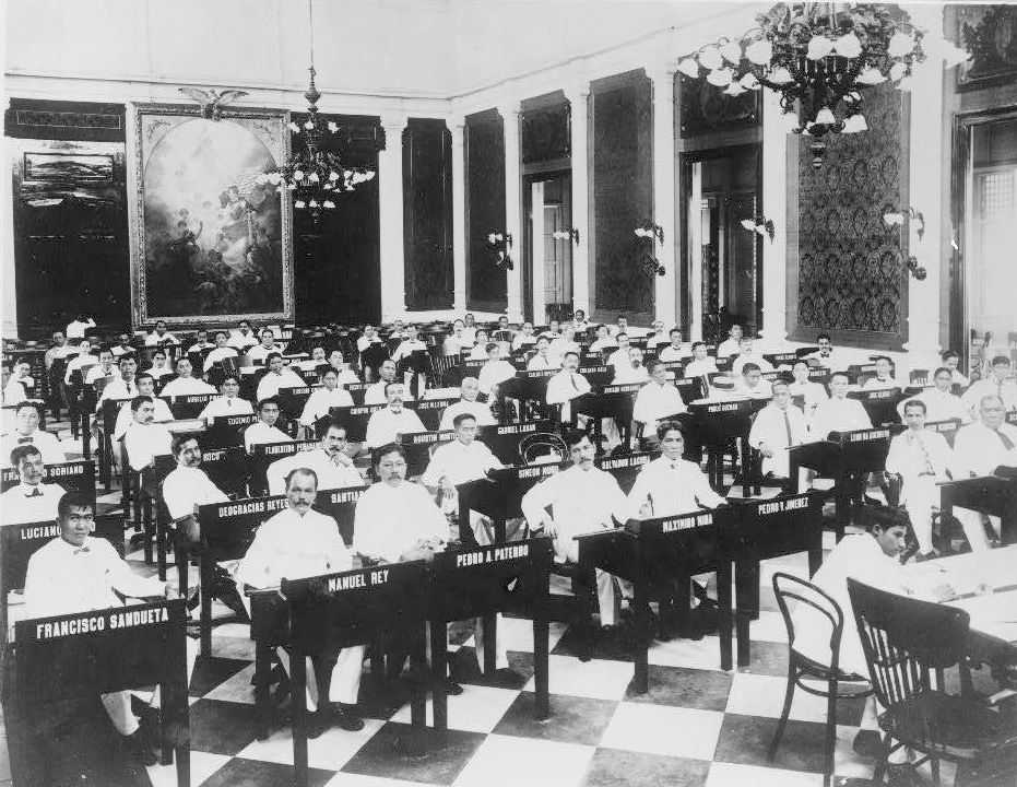 Black and white photo of large room in legislative building filled with Filipino political figures seated at desks