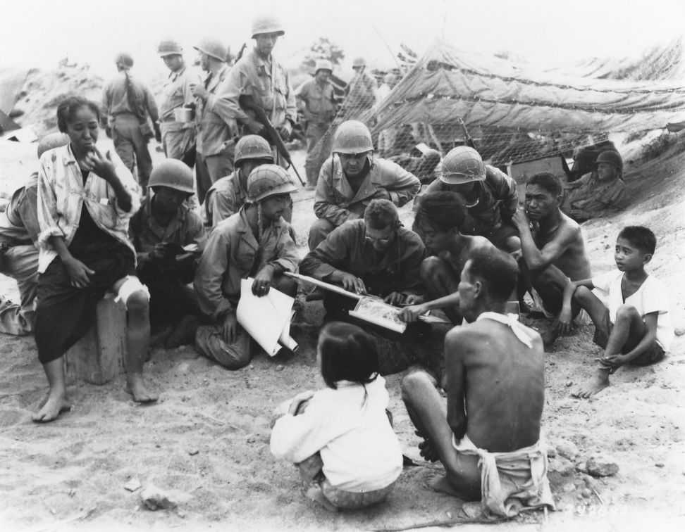 Photo of Soldiers and Filipinos with children gathered around a document