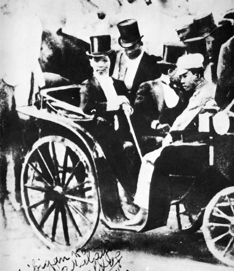 Black and white photo of men in suits riding in a carriage