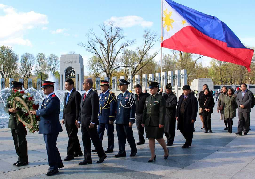 Ceremony at WWII memorial with veterans and the Philippine flag. 